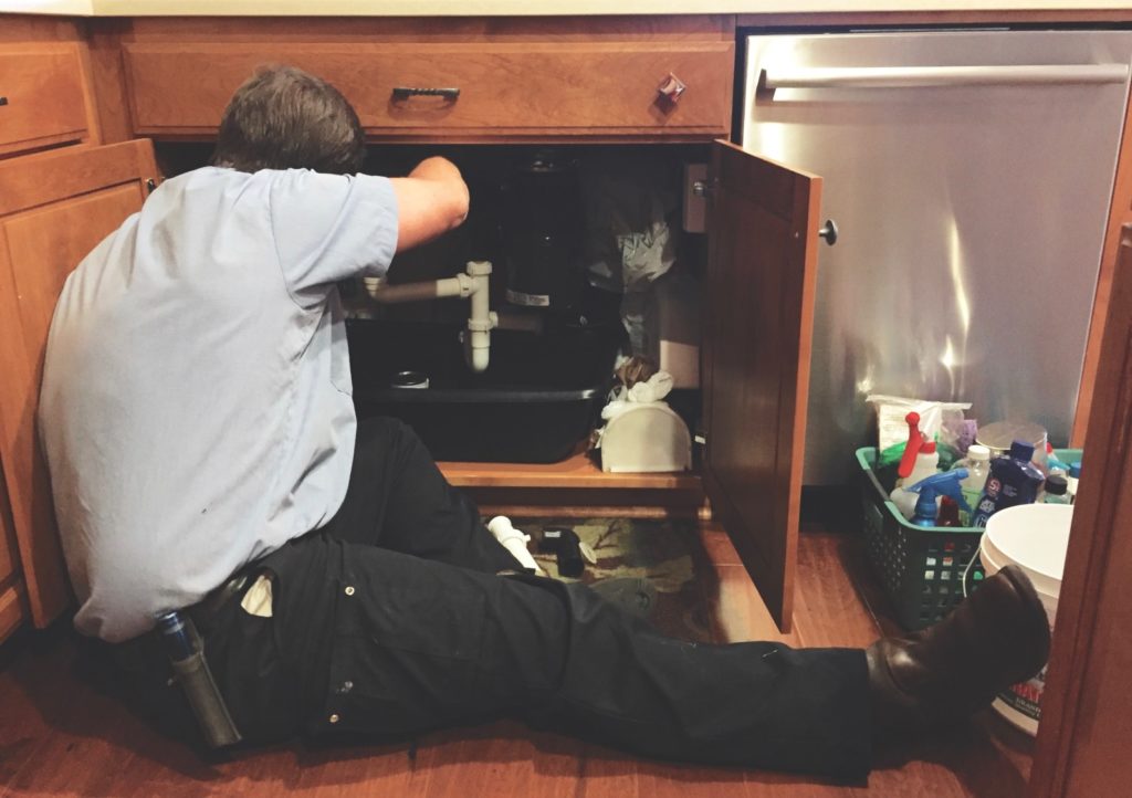 An after-hours plumber working under the sink